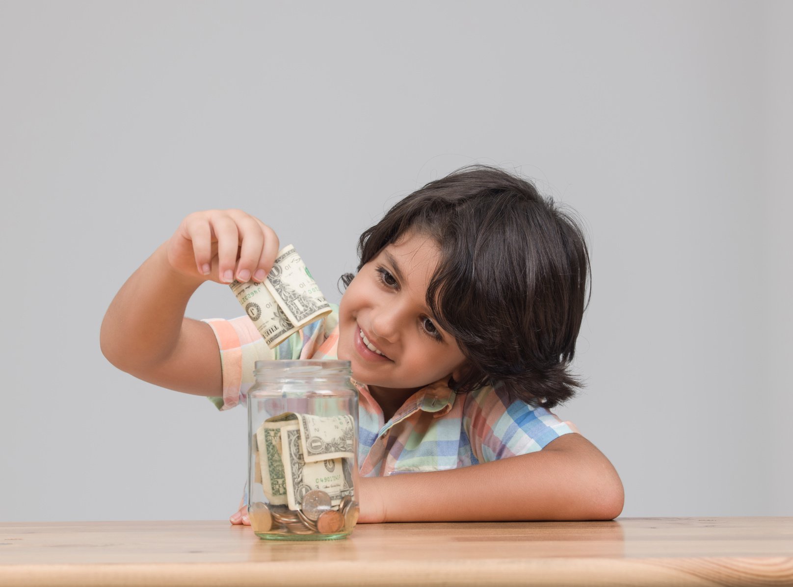 Portraiit of child putting money in savings jar