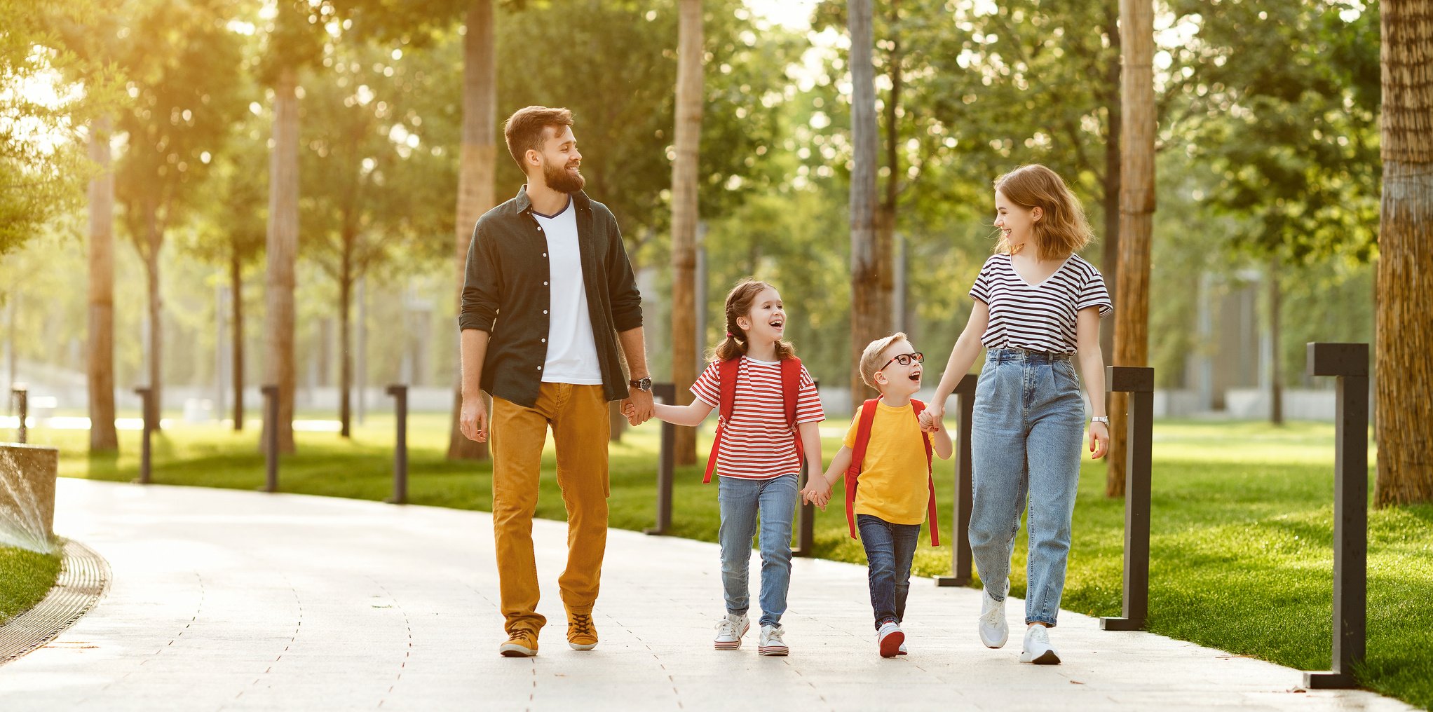 Happy family walking to school in park